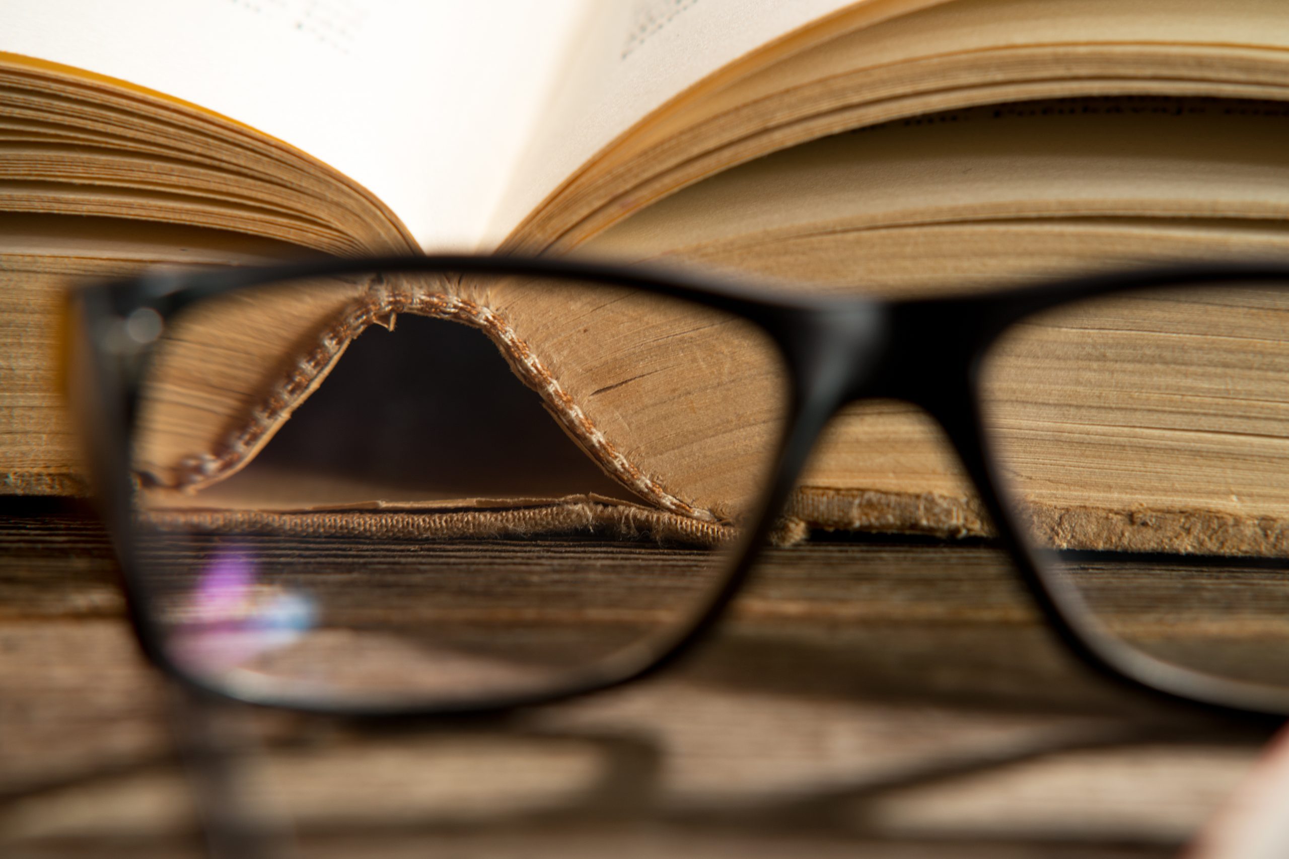 Eine Brille liegt vor einem Buch.