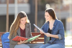 Zwei Studierende sitzen auf einer Bank und lernen gemeinsam.